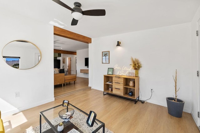 living room with ceiling fan, beam ceiling, and light wood-type flooring