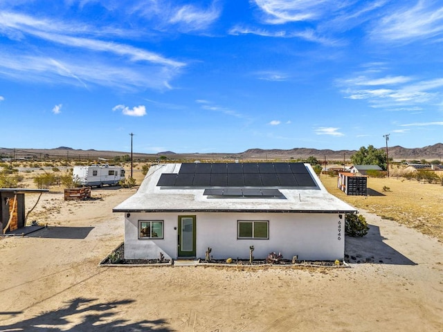 view of front of home with a mountain view and solar panels