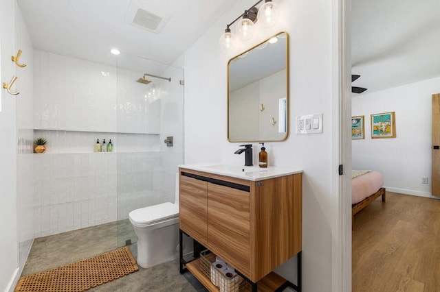 bathroom with hardwood / wood-style flooring, vanity, toilet, and tiled shower