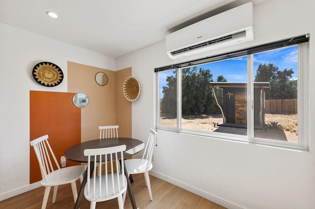 dining space with light hardwood / wood-style floors and an AC wall unit