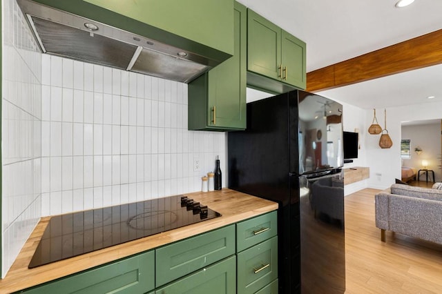 kitchen with light wood-type flooring, black appliances, exhaust hood, green cabinetry, and butcher block counters