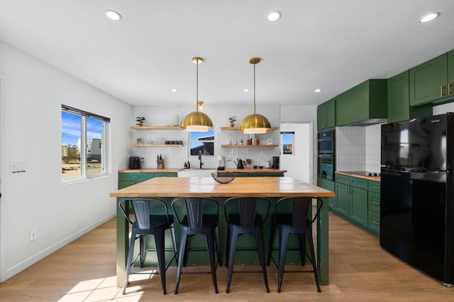 kitchen featuring tasteful backsplash, wooden counters, black appliances, and green cabinetry