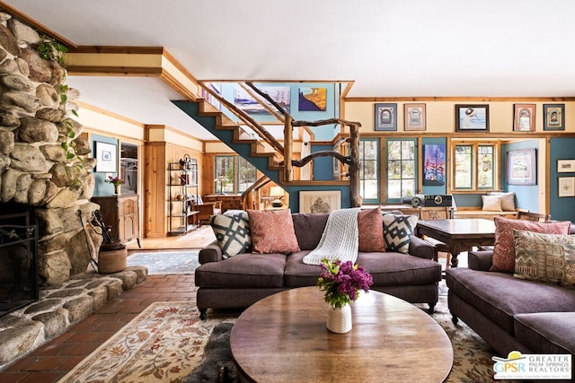 living room featuring a wealth of natural light, ornamental molding, and a stone fireplace