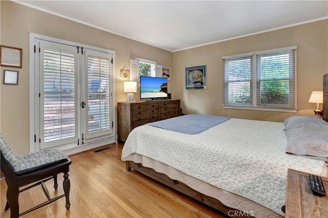 bedroom featuring access to exterior, light hardwood / wood-style floors, and crown molding