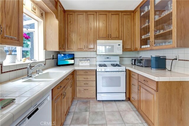 kitchen with white appliances, tasteful backsplash, tile counters, and sink