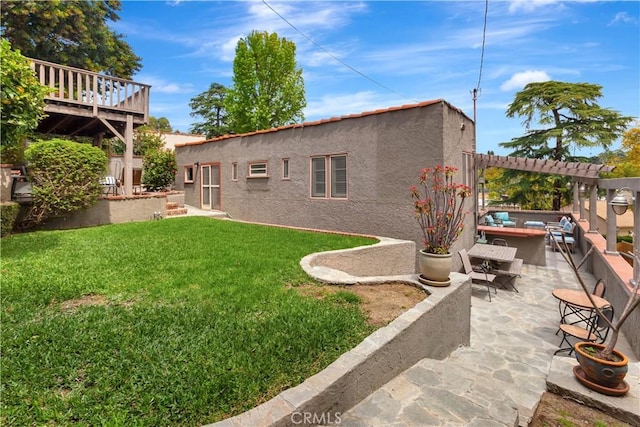 back of house featuring a patio, a deck, a pergola, and a lawn