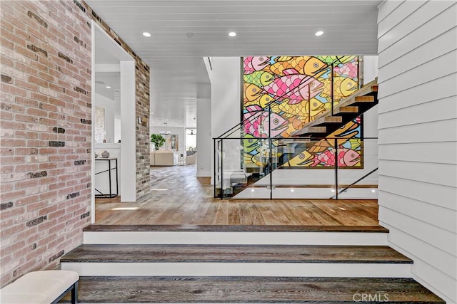 stairway with hardwood / wood-style flooring and brick wall