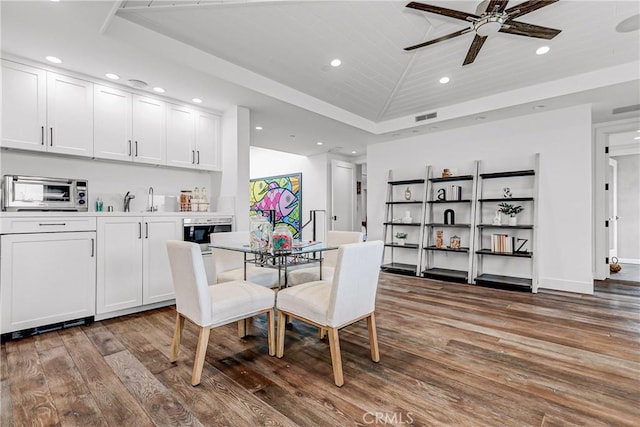 dining room featuring dark wood-type flooring, ceiling fan, sink, and vaulted ceiling