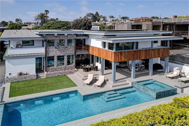 rear view of house featuring a swimming pool with hot tub and a patio