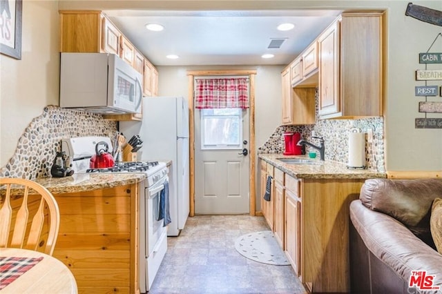 kitchen featuring light stone countertops, backsplash, white appliances, sink, and light brown cabinets