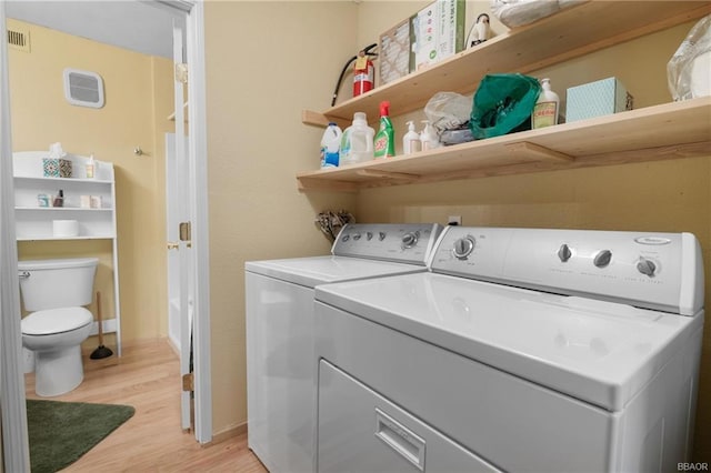 clothes washing area with separate washer and dryer and light wood-type flooring