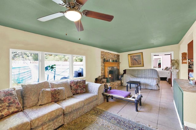 tiled bedroom with ceiling fan, a stone fireplace, and vaulted ceiling