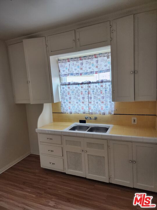 kitchen featuring white cabinets, tile countertops, sink, and dark hardwood / wood-style flooring