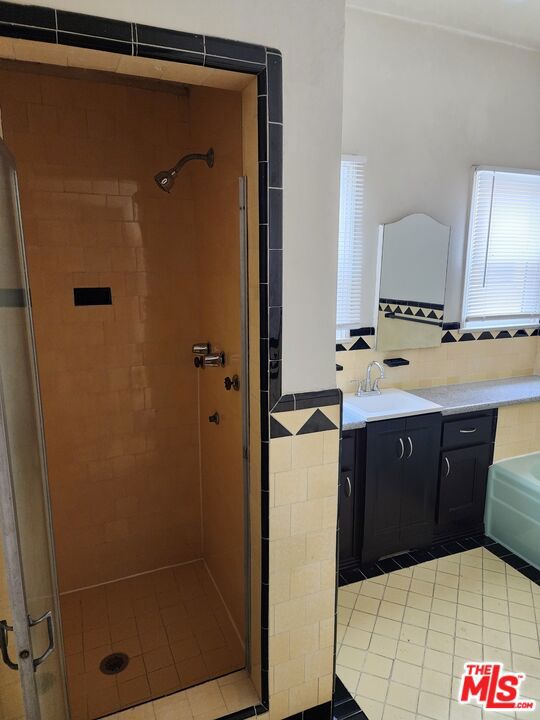 bathroom with an enclosed shower, vanity, and tile flooring