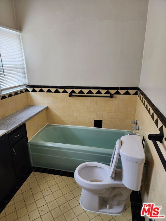 bathroom featuring tile floors, toilet, a bathtub, and vanity