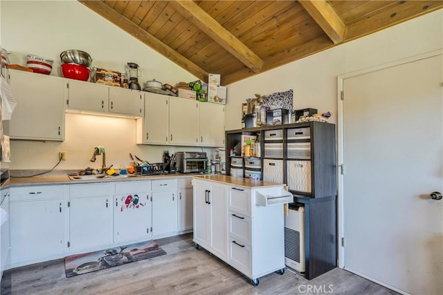 kitchen with wooden ceiling, white cabinets, lofted ceiling with beams, sink, and light wood-type flooring