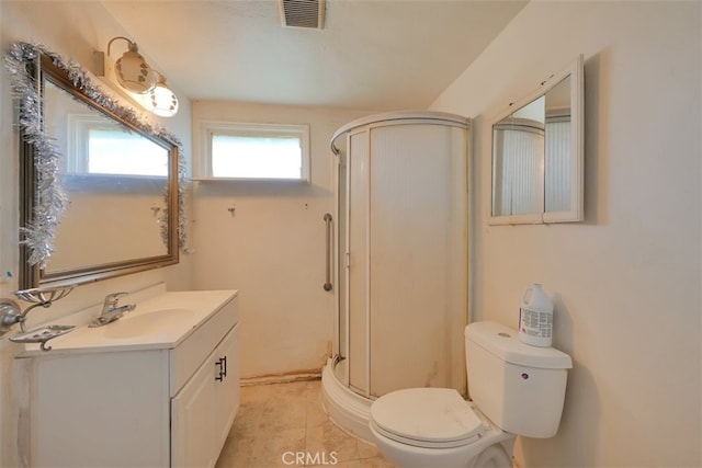 bathroom featuring tile patterned flooring, vanity, toilet, and a shower with shower door