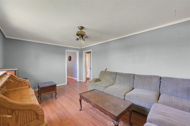 living room featuring ceiling fan, ornamental molding, and light hardwood / wood-style flooring