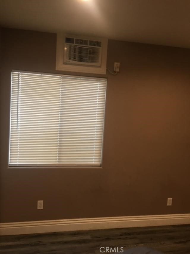 unfurnished room featuring a wall mounted AC and dark hardwood / wood-style flooring