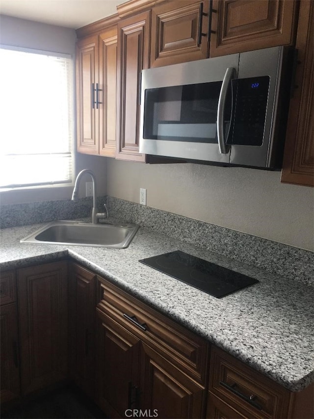 222 F St, Needles, CA 92363 - kitchen with stainless steel microwave, a sink, black electric stovetop, and light countertops