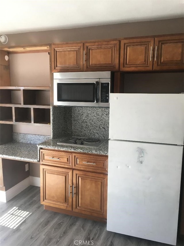 222 F St, Needles, CA 92363 - kitchen featuring appliances with stainless steel finishes, light wood-style flooring, brown cabinetry, stone counters, and open shelves