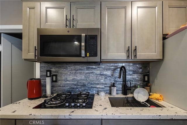 222 F St, Needles, CA 92363 - kitchen with stainless steel microwave, black gas cooktop, backsplash, and a sink