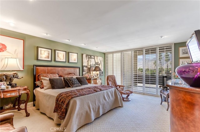 bedroom with expansive windows, light colored carpet, and access to exterior