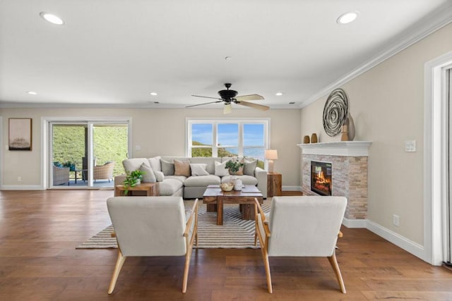 living room featuring ceiling fan, dark hardwood / wood-style floors, crown molding, and a fireplace