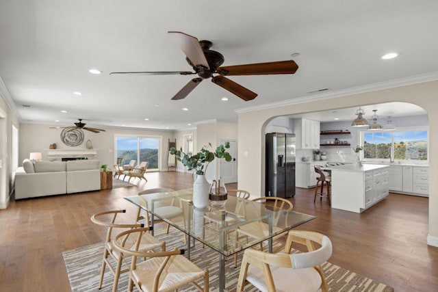 dining space with ceiling fan, crown molding, and wood-type flooring