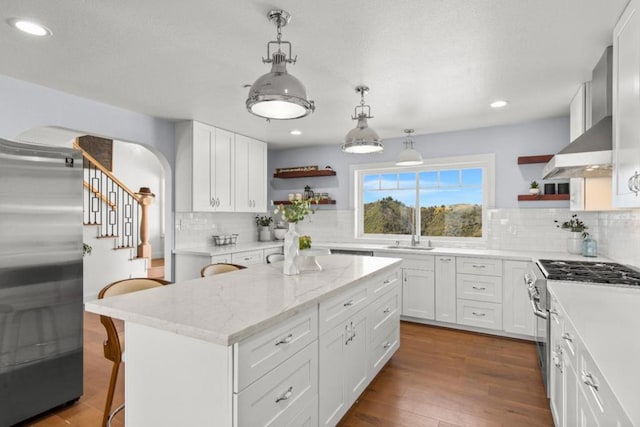 kitchen with pendant lighting, a kitchen island, stainless steel appliances, and white cabinetry