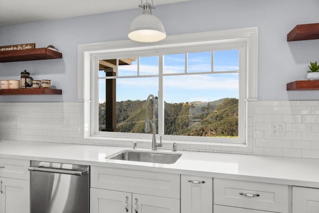 kitchen featuring white cabinetry, dishwasher, decorative light fixtures, and sink