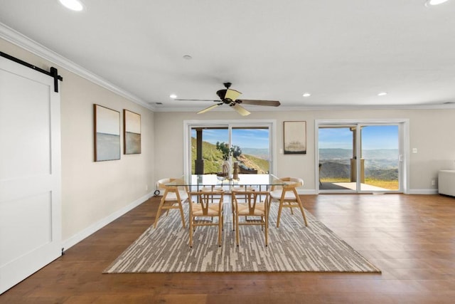 dining room with ceiling fan, dark hardwood / wood-style flooring, crown molding, and a barn door