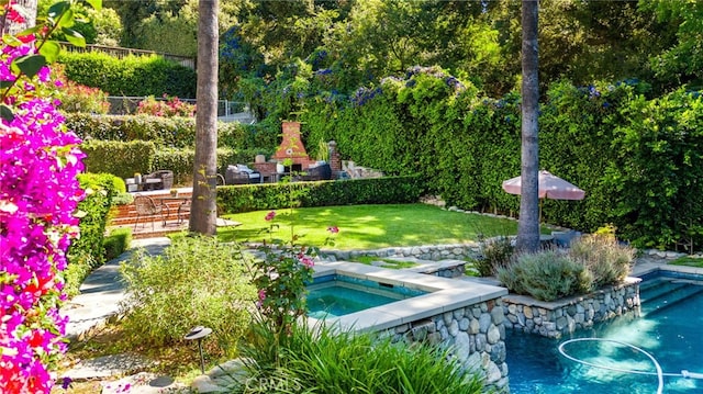 view of swimming pool featuring an in ground hot tub, an outdoor stone fireplace, and a lawn