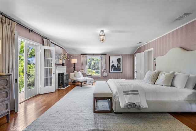 bedroom with wood-type flooring, access to outside, multiple windows, and lofted ceiling