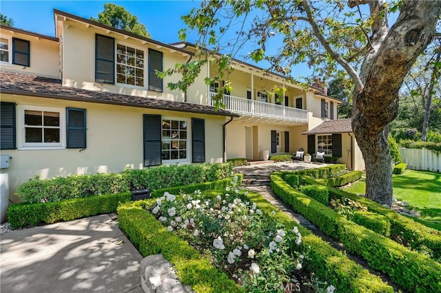 view of front of property featuring fence, a balcony, and stucco siding