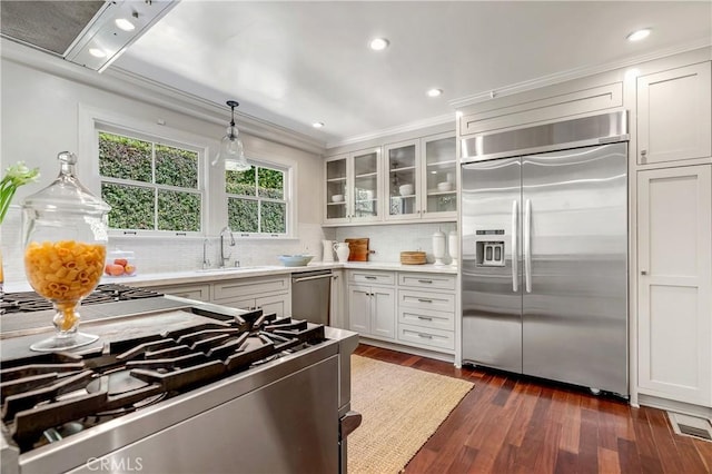 kitchen featuring white cabinetry, sink, stainless steel appliances, dark hardwood / wood-style floors, and pendant lighting