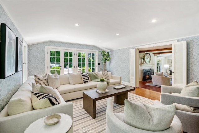 living room with french doors, light wood-type flooring, and lofted ceiling