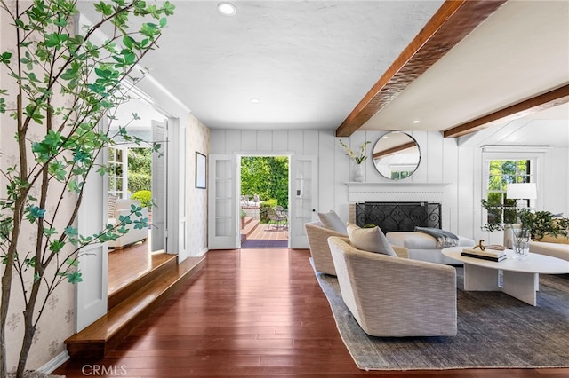 living room featuring a brick fireplace, beam ceiling, and dark wood-type flooring