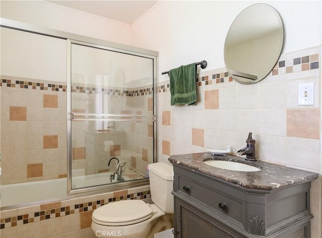 full bathroom with vanity, toilet, bath / shower combo with glass door, and tile walls