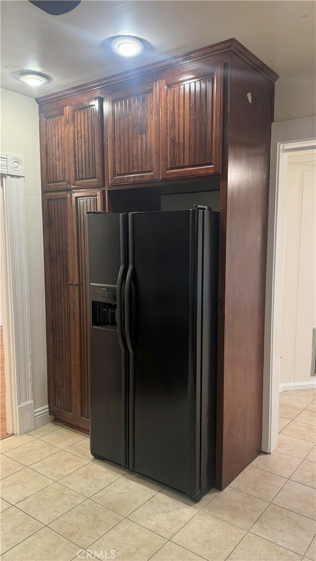 kitchen with black fridge with ice dispenser, dark brown cabinetry, and light tile patterned flooring