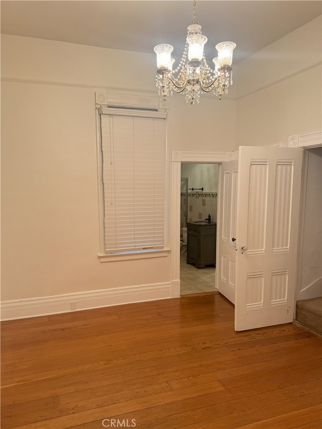 empty room featuring a notable chandelier and light hardwood / wood-style flooring