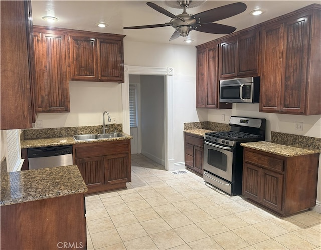 kitchen featuring ceiling fan, sink, stainless steel appliances, dark stone countertops, and light tile patterned floors