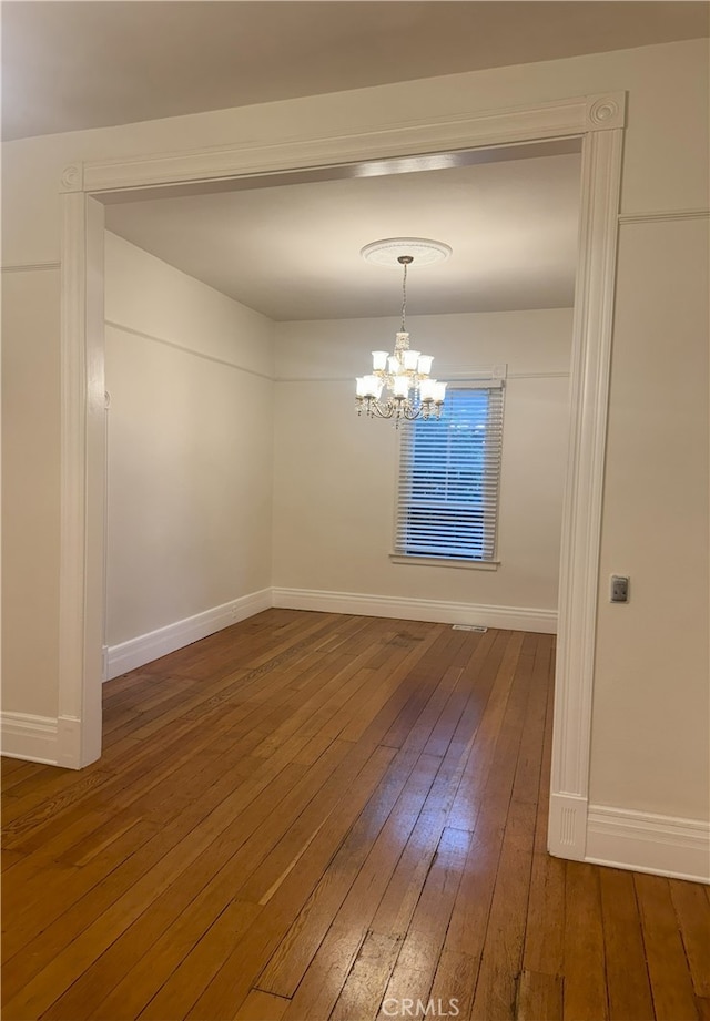 unfurnished dining area with dark hardwood / wood-style floors and a notable chandelier