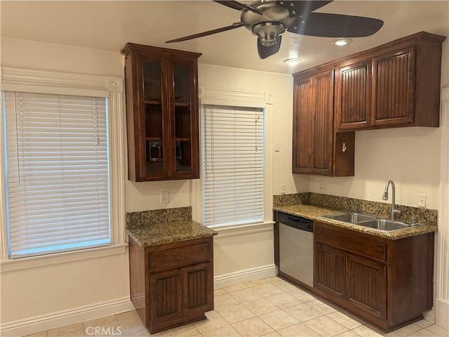 kitchen featuring ceiling fan, sink, light tile patterned floors, dark stone countertops, and dishwasher