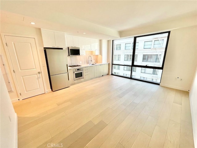 kitchen featuring white cabinetry, sink, stainless steel appliances, and light hardwood / wood-style floors