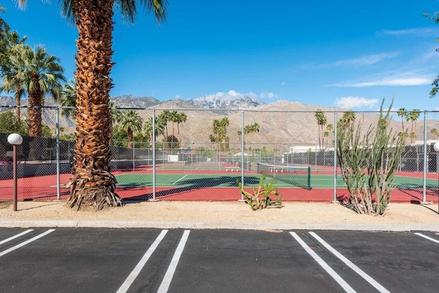 view of vehicle parking with a mountain view and tennis court