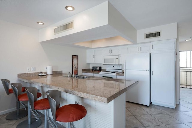 kitchen featuring a breakfast bar, white cabinets, white appliances, kitchen peninsula, and sink