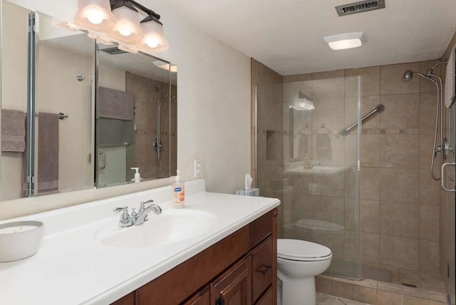 bathroom featuring tile floors, vanity with extensive cabinet space, toilet, and a shower with shower door