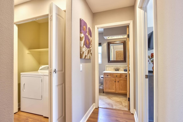 corridor featuring washing machine and clothes dryer, sink, and light hardwood / wood-style floors