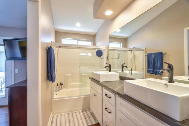 bathroom featuring hardwood / wood-style floors, vanity, shower / bath combination with glass door, and lofted ceiling